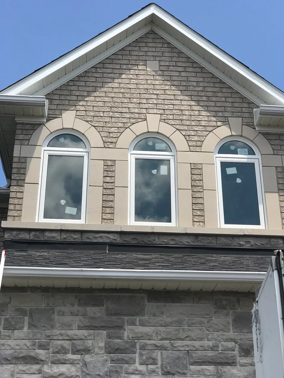 Three tall white windows with arched transoms in a stone facade