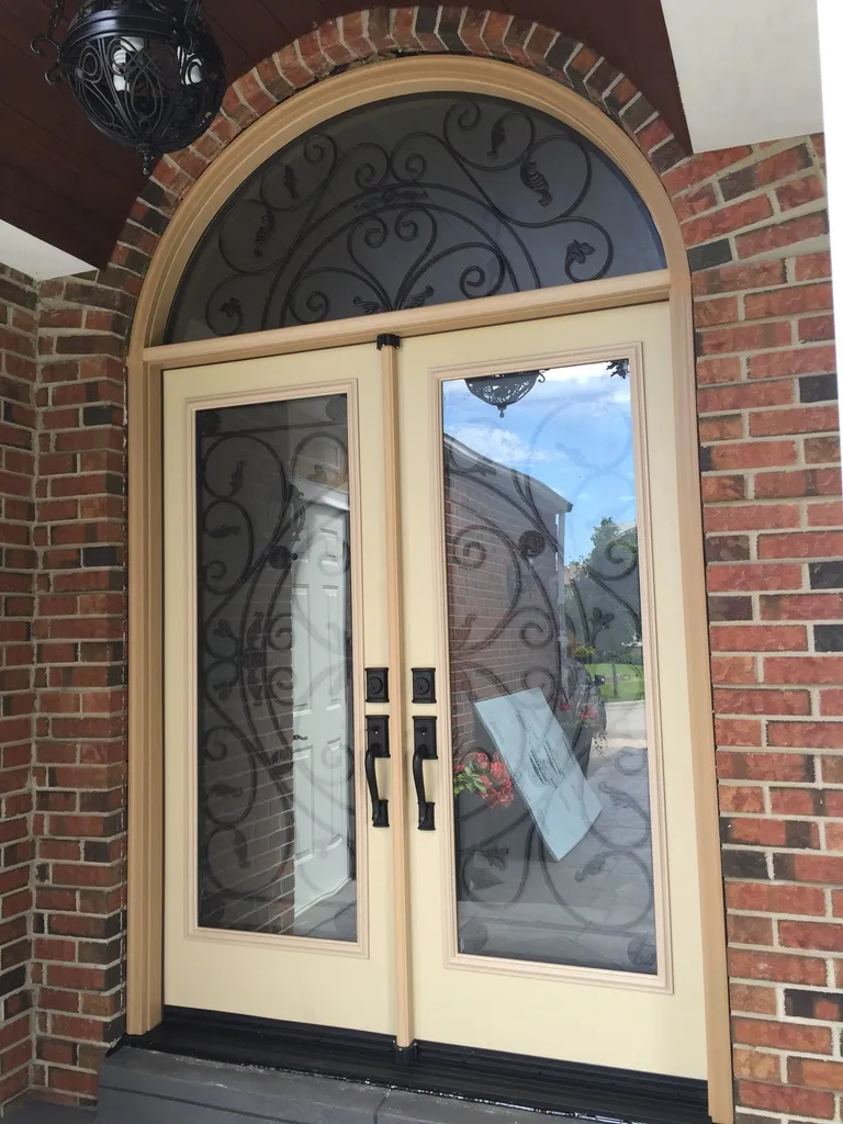 Beige double entry doors with decorative glass and an arched transom