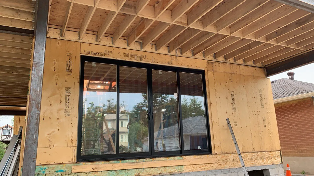 Large black multi-panel patio door installed in a framed wall opening