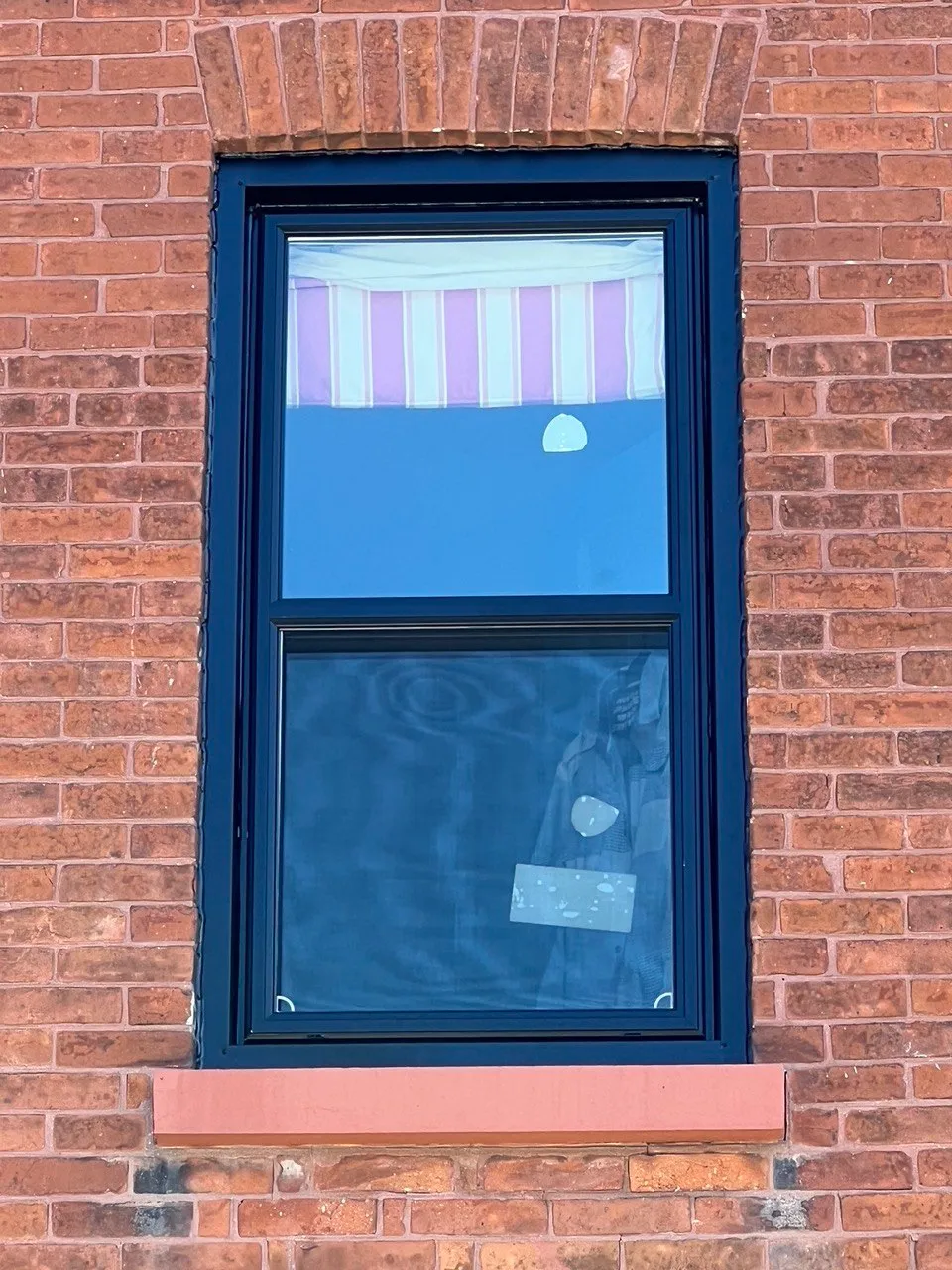 Tall black-framed window in a red brick wall