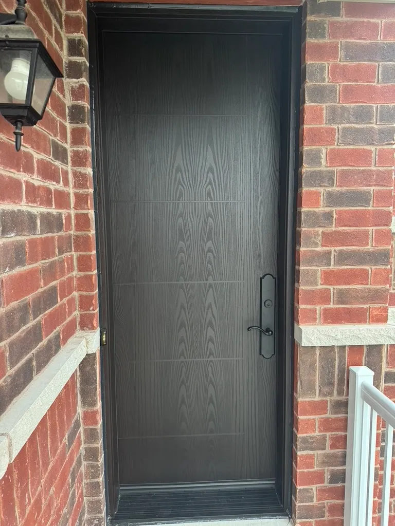 Black wood-grain entry door in a brick exterior wall