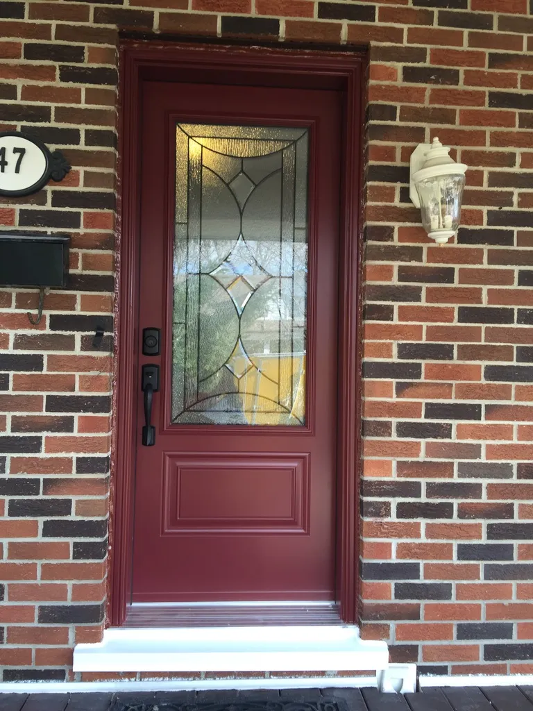 Burgundy entry door with a decorative glass insert