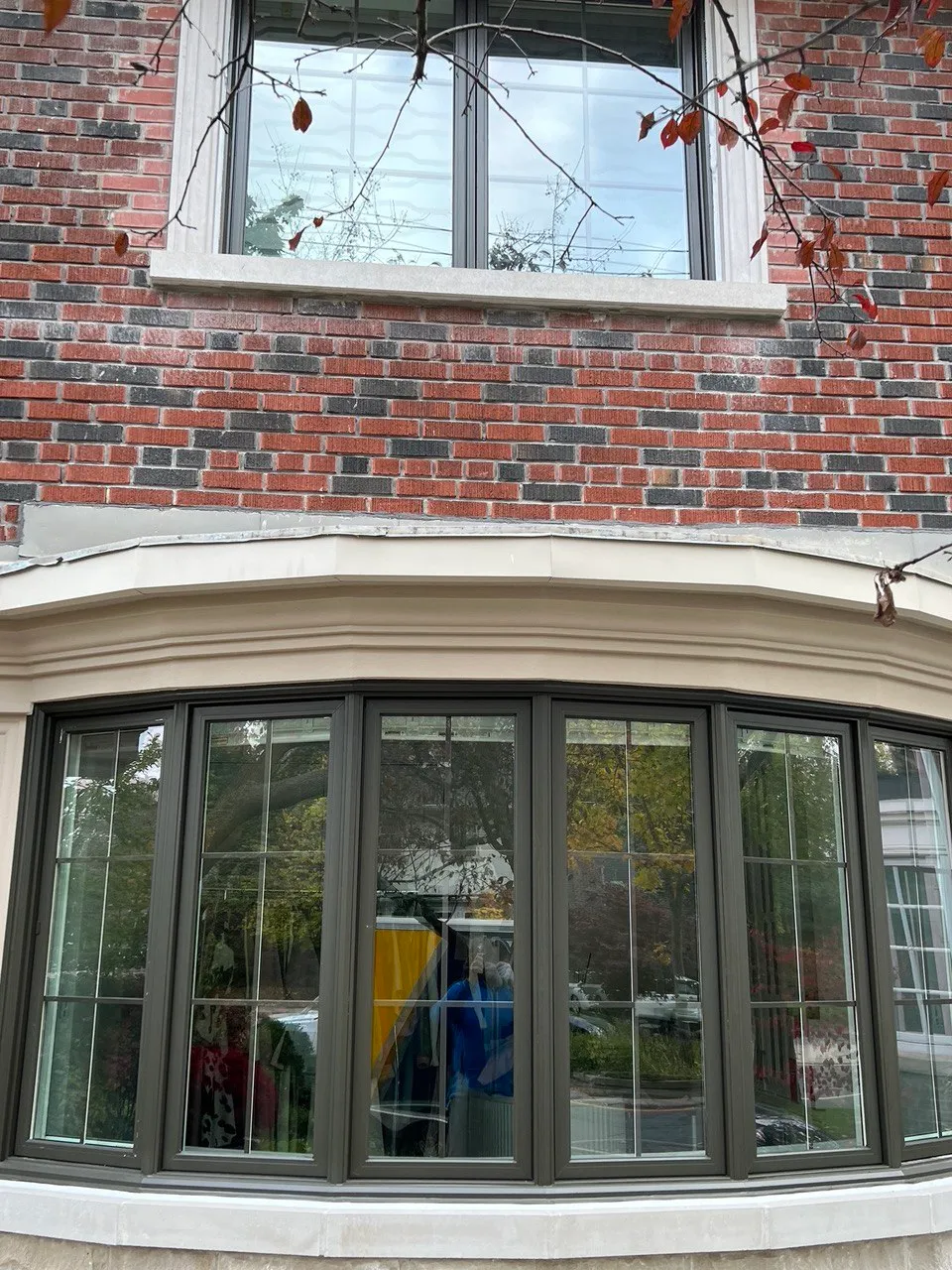 Dark-framed bay window in a brick exterior wall