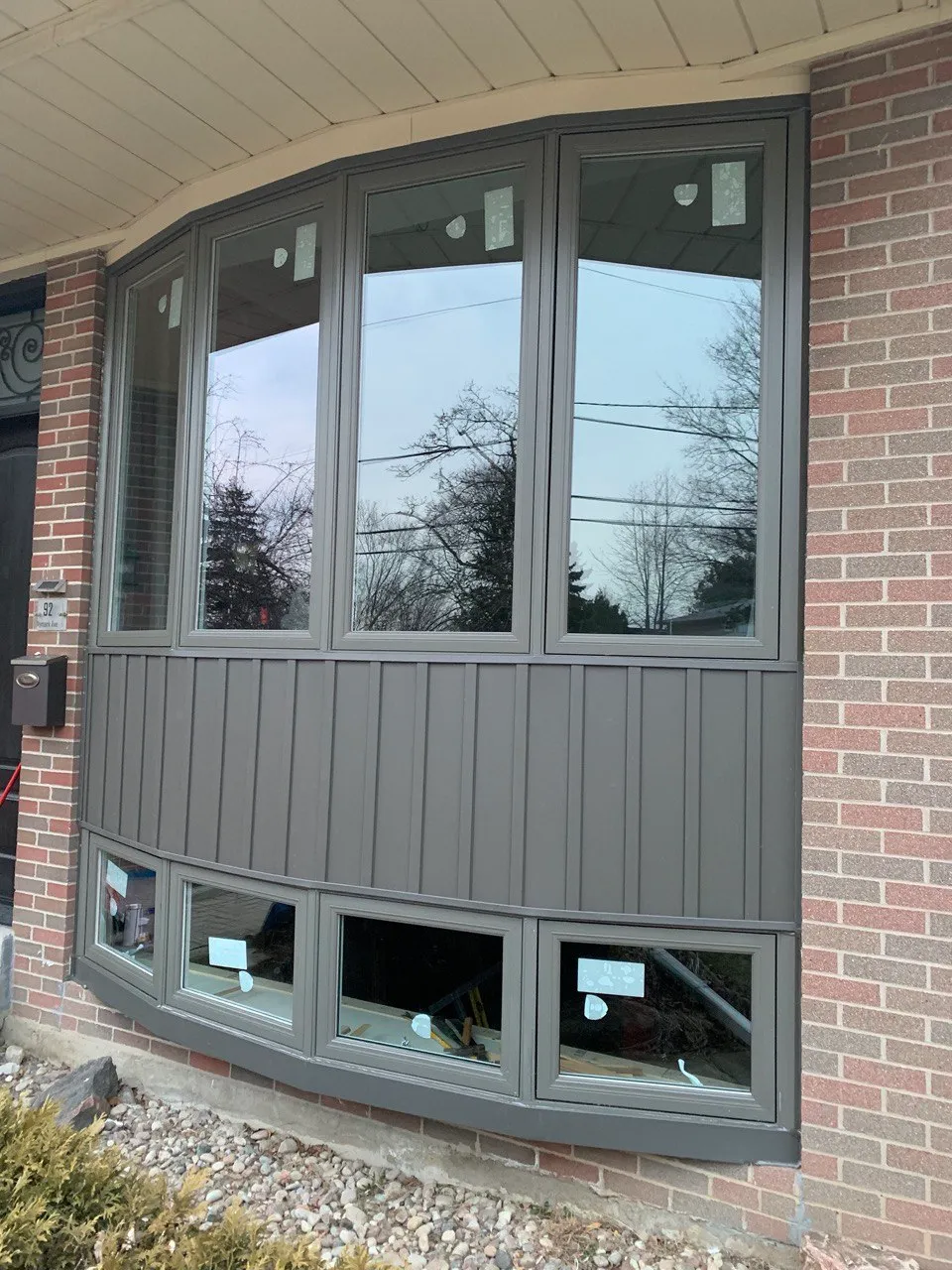 Grey-framed bay window in a brick exterior wall