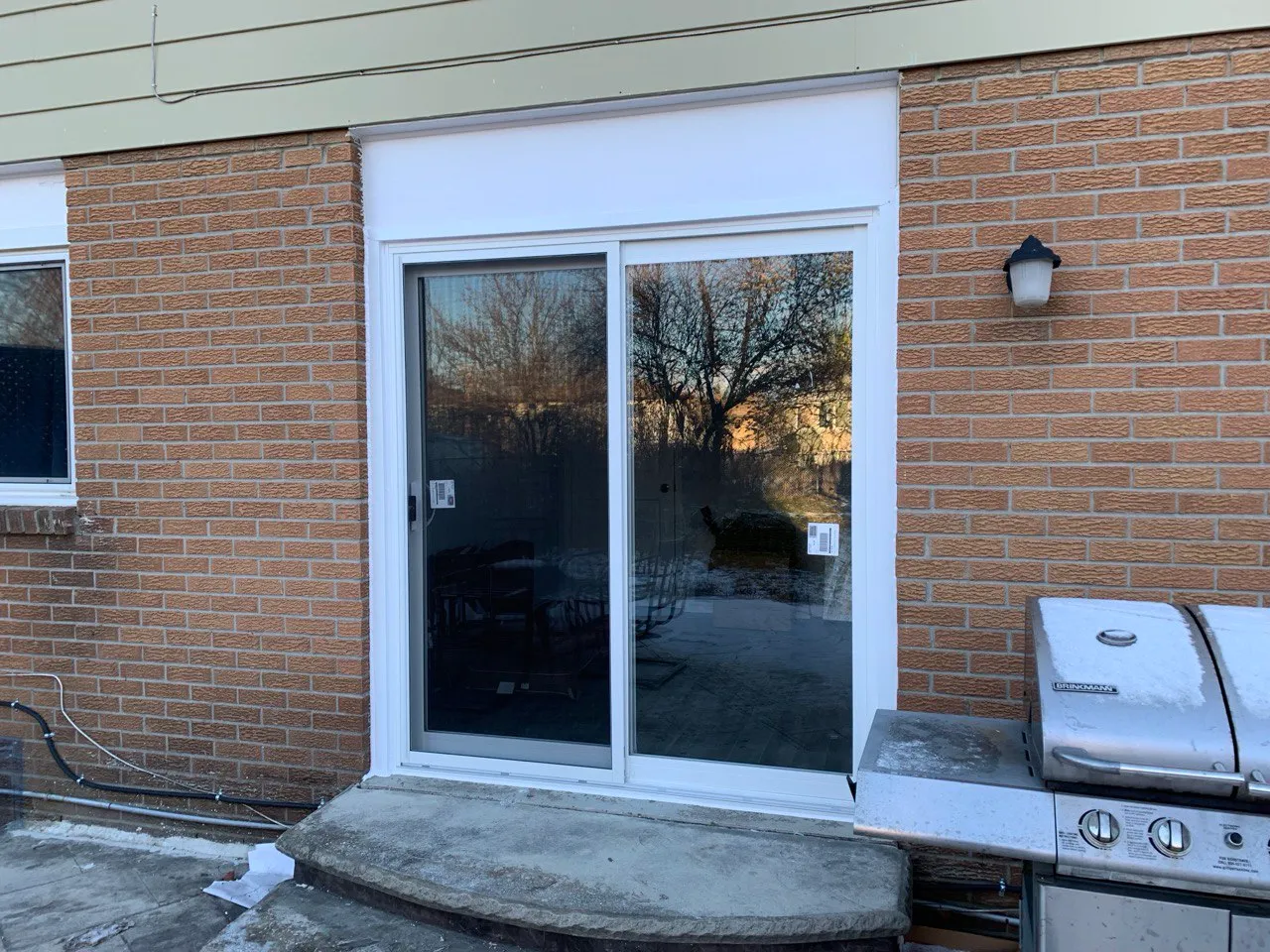 Grey-framed patio sliding door in a brick exterior wall