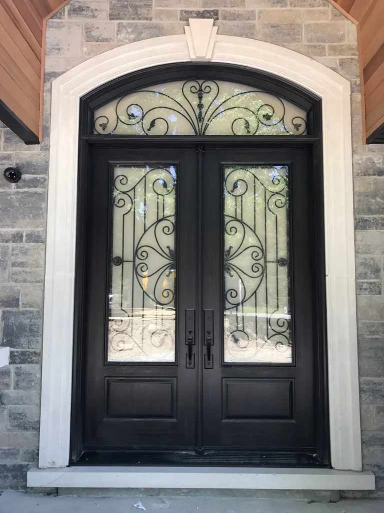 Dark double entry doors with ornate glass and an arched transom