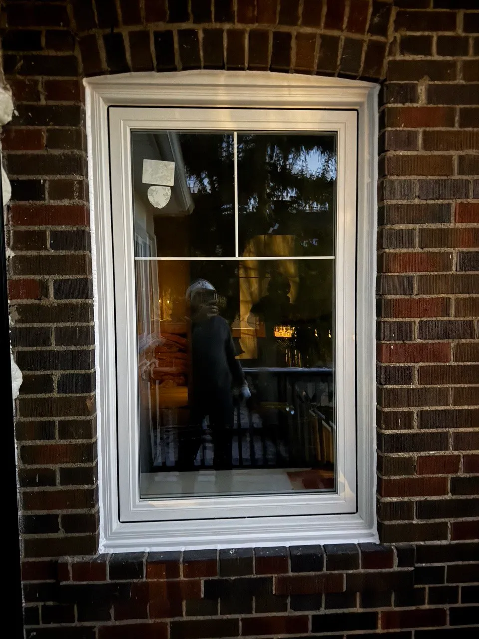 Single white-framed casement window in a dark brick wall