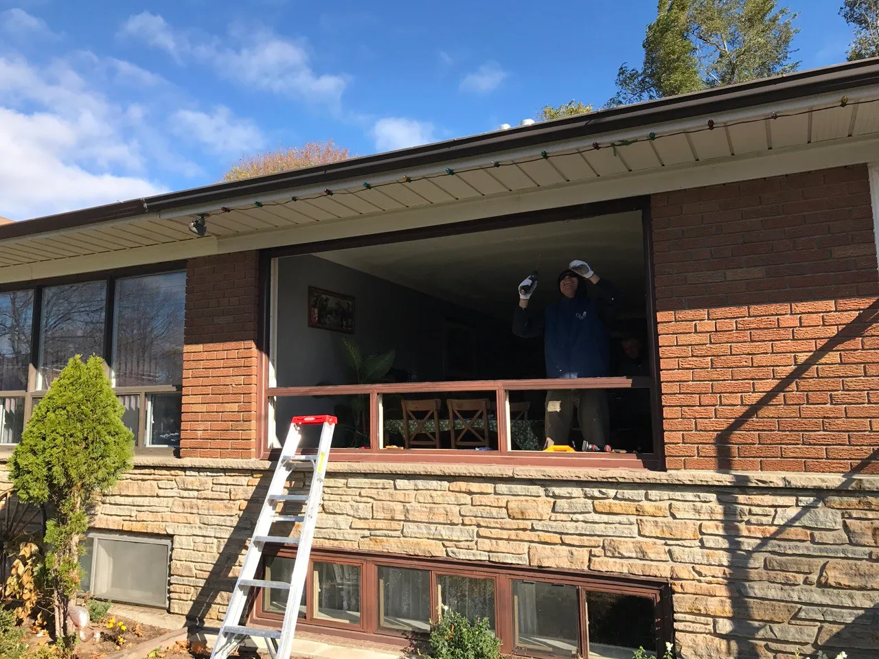 Installer working at a large window opening in a brick home