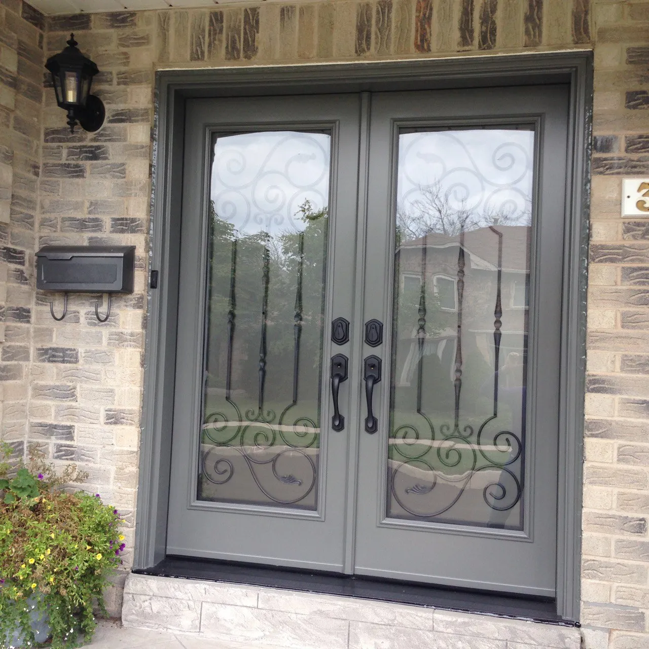Grey double entry doors with decorative glass in a stone exterior wall