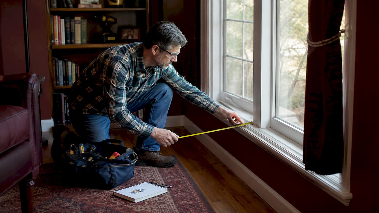 Man measuring bay window inside living room